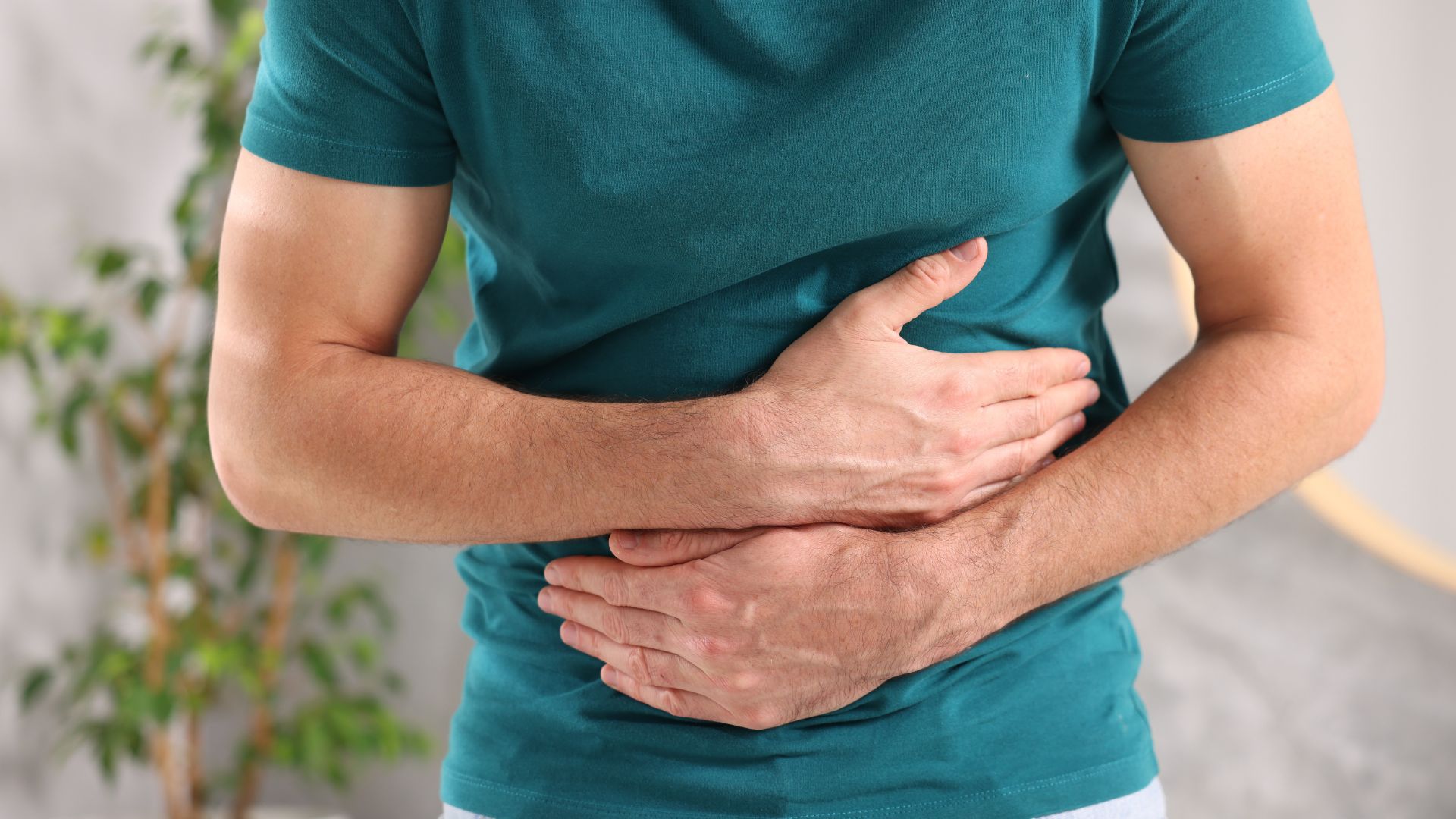 infecção intestinal homem com mãos na barriga, em sinal de dor de barriga