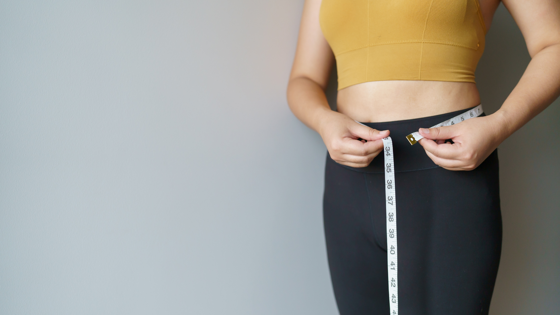 Mulher medindo a barriga com fita métrica