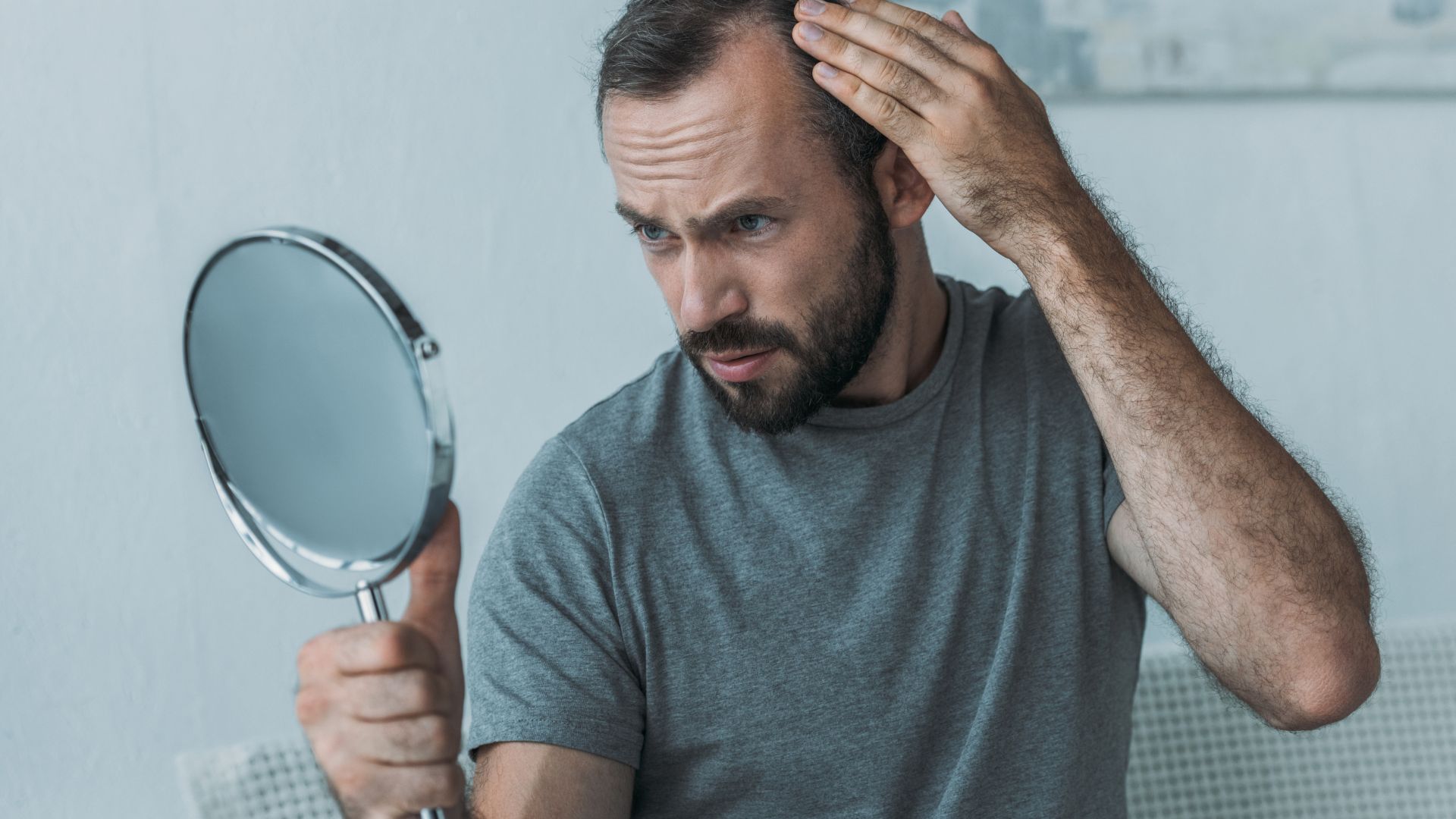 homem olhando falha no cabelo no espelho