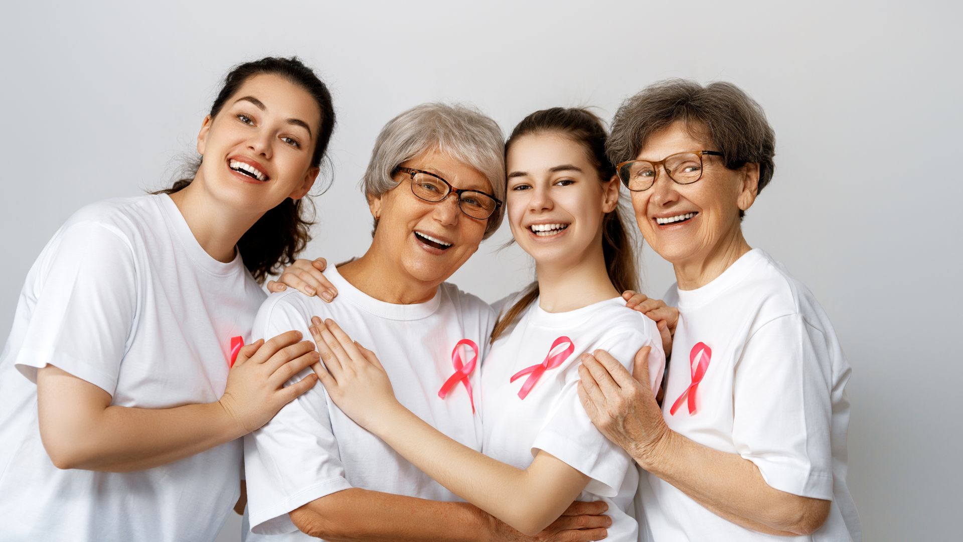 grupo de mulheres de diferentes idades com camiseta com laço rosa